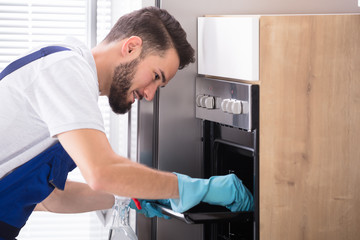 Janitor Cleaning Oven In Kitchen