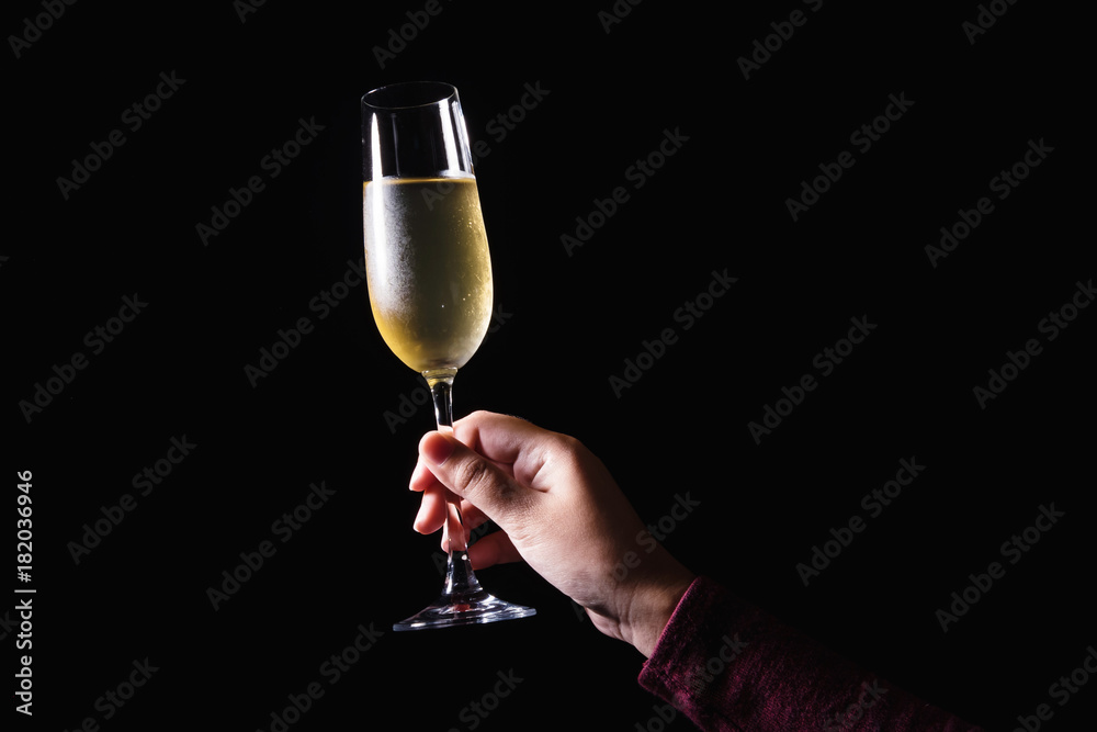 Wall mural woman hand holding glasses of champagne on the black background