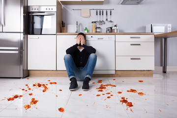 Man Sitting On Kitchen Floor With Spilled Food