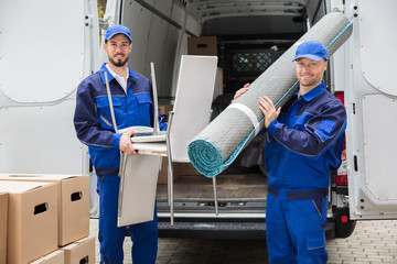 Two Delivery Men Holding Chairs And Carpet