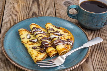 Pancakes stuffed with chocolate sauce, for breakfast on wooden table