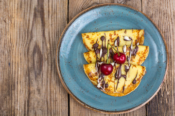 Pancakes stuffed with chocolate sauce, for breakfast on wooden table