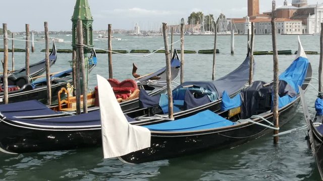 Beautiful black gondolas stand and rock on the waves of Grand Canal in Venice