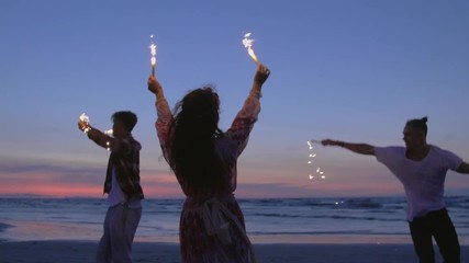 Hippie friends dancing on a beach at dusk - Powered by Adobe