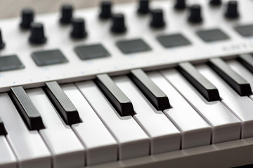 White MIDI keyboard with pads and faders.