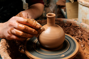 Potter at work. Workshop. Hands of a potter, creating an earthen jar on the circle