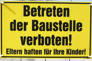 Gelbes Schild Betreten der Baustelle verboten an einem Metallzau
