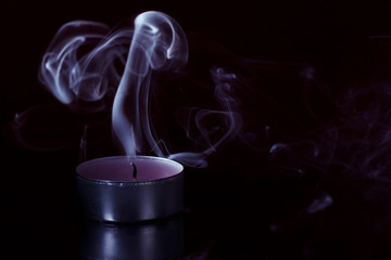 Smoke and extinct candle on a black background