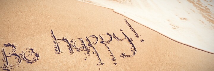Be happy text written on sand