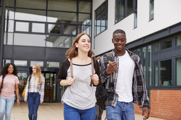 Group Of Students Walking Outside College Buildings