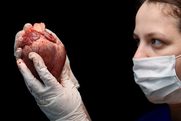 abstract illegal organ transplantation. A human heart in the hand of a surgeon woman. International...