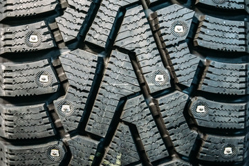 New winter tire with steel thorns, black rubber texture of car wheel