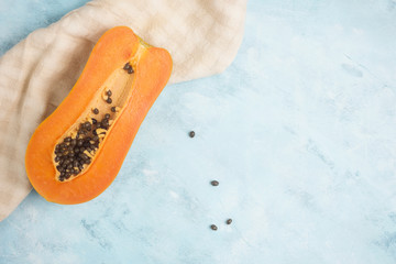 Half of colorful orange papaya fruit on kitchen tissue on blue and white table. Healthy vegetarian food concept. Detox