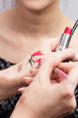 The make-up artist tests and selects the color of the pencil for the lips before applying to the face of the model. Hands make-up artist with lipstick and lip liner close-up samples