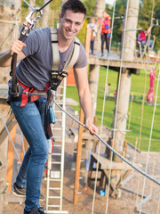 Mann balanciert über Seil im Kletterpark
