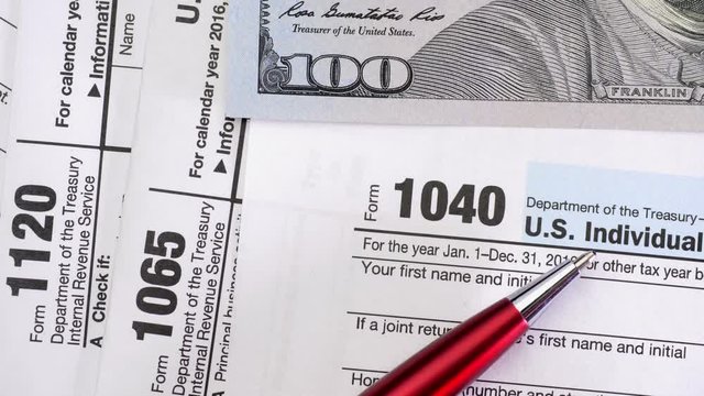 Tax Form 1040, 1120, 1065 and dollar bills, close up
