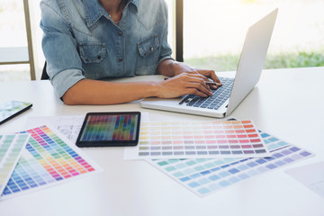 Creative creativity graphic designer working with graphics tablet,laptop and smart phone, colour chart at workplace on wooden desk, colour ideas style concept