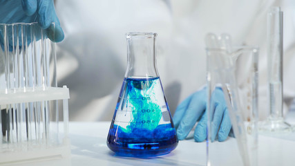 Close-up of conical flask with blue liquid, chemical experiment at laboratory - obrazy, fototapety, plakaty
