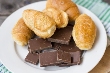 croissants and chocolate chunks in a white plate on a wooden table