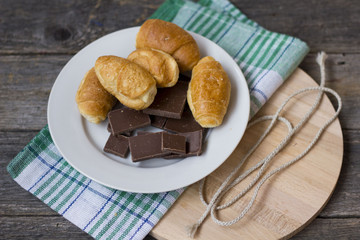 croissants and chocolate chunks in a white plate on a wooden table