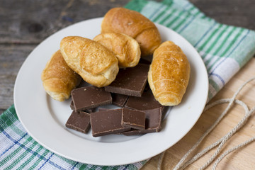 croissants and chocolate chunks in a white plate on a wooden table
