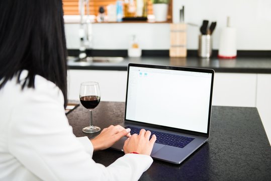 Beautiful young girl with a laptop and a wine glass