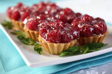 Dessert of pastry with whipped cream decorated with raspberries and drizzled with a sweet jelly.