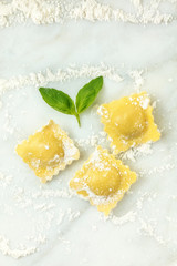 Overhead photo of ravioli with flour and basil leaves