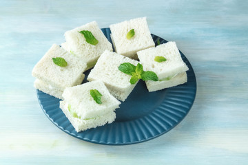 Plate of cucumber sandwiches on teal blue background