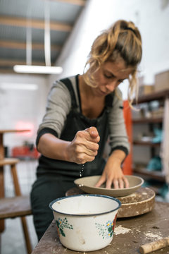 Woman moistening piece of clay