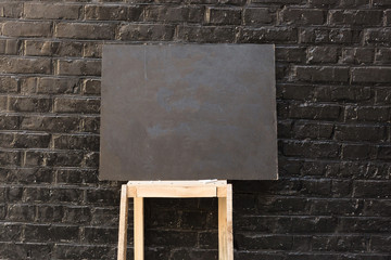 teaching, arts and crafts, advertising concept. on the light wooden support shelf there is small blackboard on the background of the brick wall in the same shade