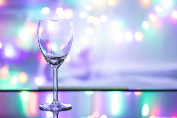Close up view and copy space. Empty wine glass is on the table and the background is the colorful of sparkling light.
