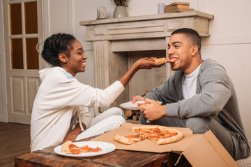 woman feeding man pizza