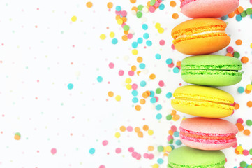 Colorful macarons on bright festive decor background, selective focus, toned