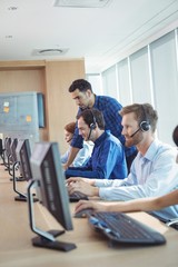 Male supervisor talking with telemarketer at call center