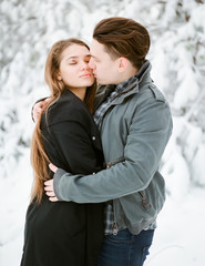 Young couple kissing in winter park. Family Outdoors.