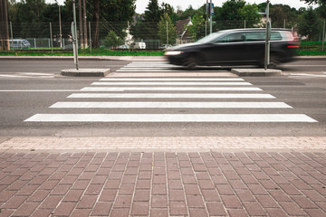 A black car at high speed crosses a pedestrian crossing, a blur effect. Streen racing.