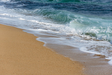 Ocean wave and foam on sandy beach, beach background