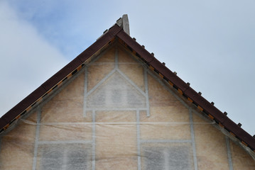 New house wall facade insulation against blue sky. Roof or attic warming with mineral wool.