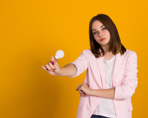 Young cute woman with electric bulb, studio  