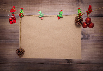 Christmas background with copy space. Vintage sheet of paper hangs on clothespins with decorative elements over wooden backdrop.
