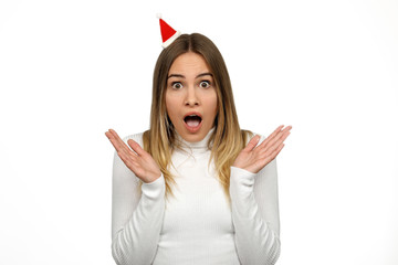 Hübsche blonde Frau mit kleiner Weihnachtsmütze schaut überrascht