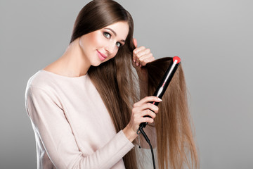 woman ironing hair with hair iron. 