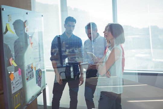 Business Entrepreneurs Standing By Whiteboard Seen Through Glass