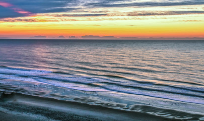 Ocean Coastal Sunrise Background. View of Atlantic coast with waves crashing on the shore and a sunrise at the horizon. Shot from above high angle view with copy space. Myrtle Beach, South Carolina.