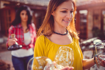 Woman carrying wine glasses at backyard patio