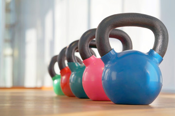 Naklejka na ściany i meble Colorful kettlebells in a row in a gym