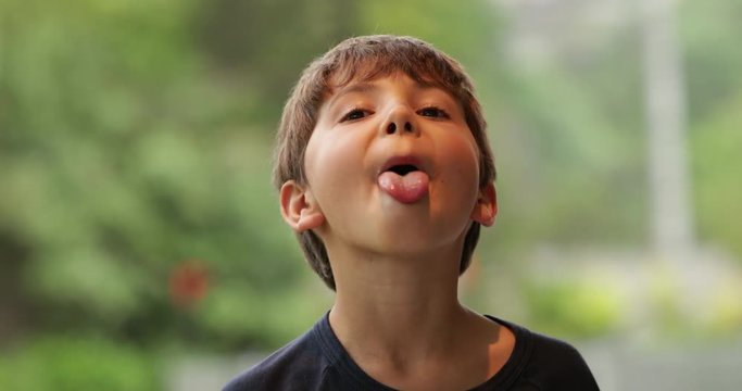 Young child sticking tongue out misbehaving in 4k. Disobedient kid sticks tongue out to camera