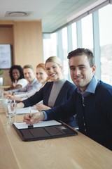 Portrait of smiling businessman with colleagues sitting at
