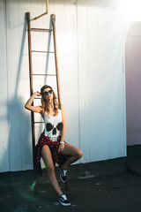 Sexy brunette girl in a black bodysuit with cap posing outdoor, urban background